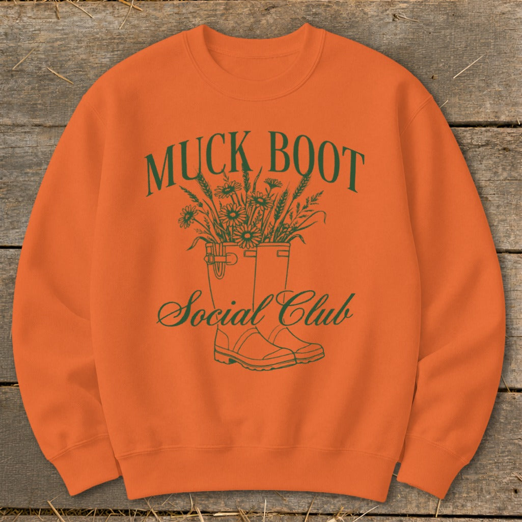 Orange sweatshirt with green "Muck Boot Social Club" text and floral design.