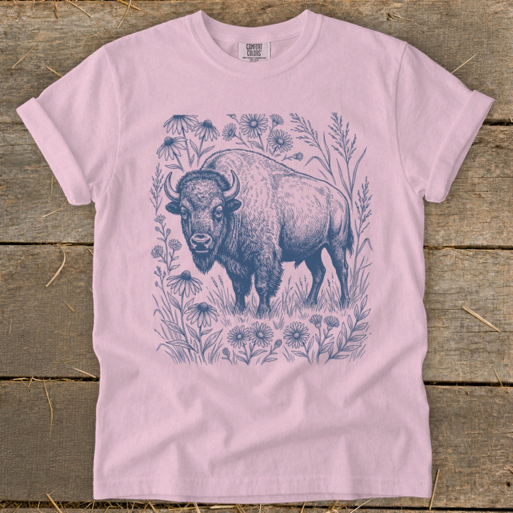 Pink t-shirt with a blue ink drawing of a bison surrounded by wildflowers and grass.