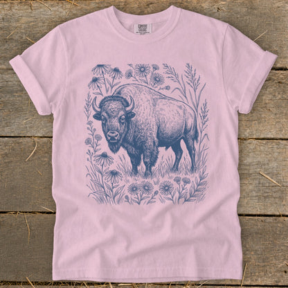 Pink t-shirt with a blue ink drawing of a bison surrounded by wildflowers and grass.