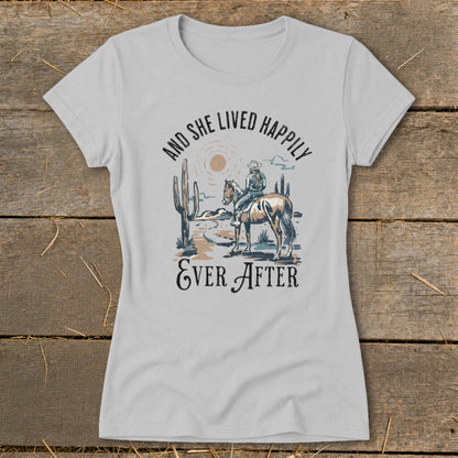 Light gray t-shirt with "And She Lived Happily Ever After" text and desert scene.