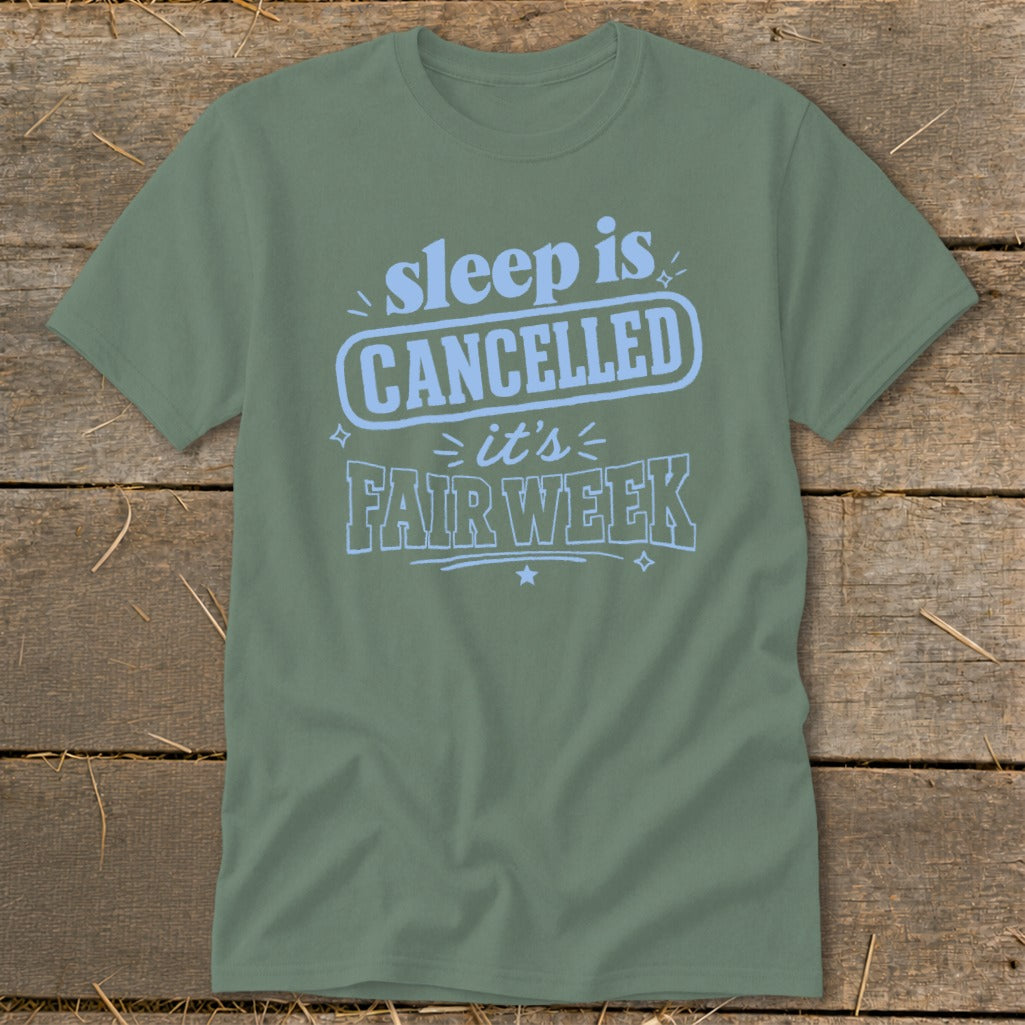 Olive t-shirt with light blue text reading "sleep is CANCELLED it's FAIR WEEK".