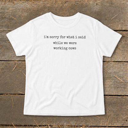 White t-shirt with black text reading "i'm sorry for what i said while we were working cows".