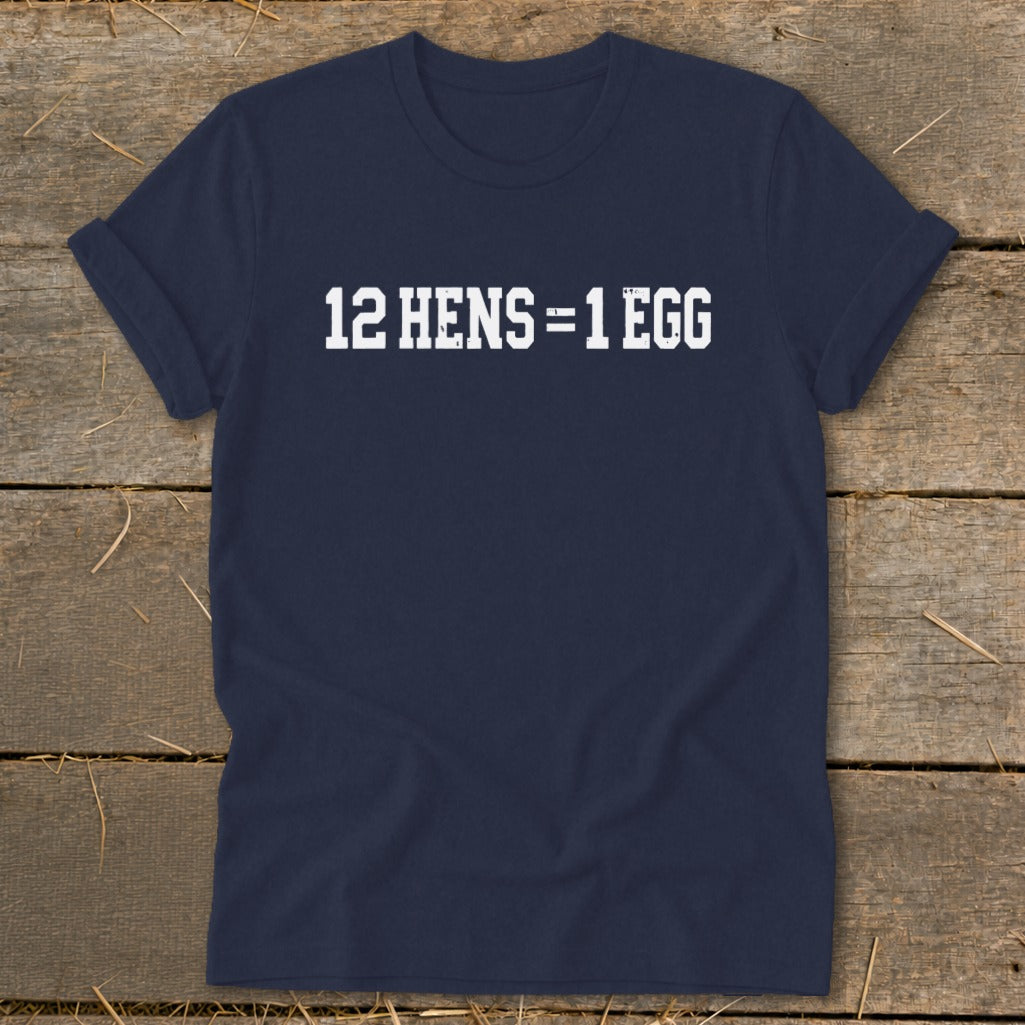Dark blue short-sleeve t-shirt with white block text reading "12 HENS = 1 EGG" laid on a wooden surface.