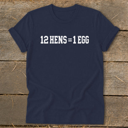 Dark blue short-sleeve t-shirt with white block text reading "12 HENS = 1 EGG" laid on a wooden surface.