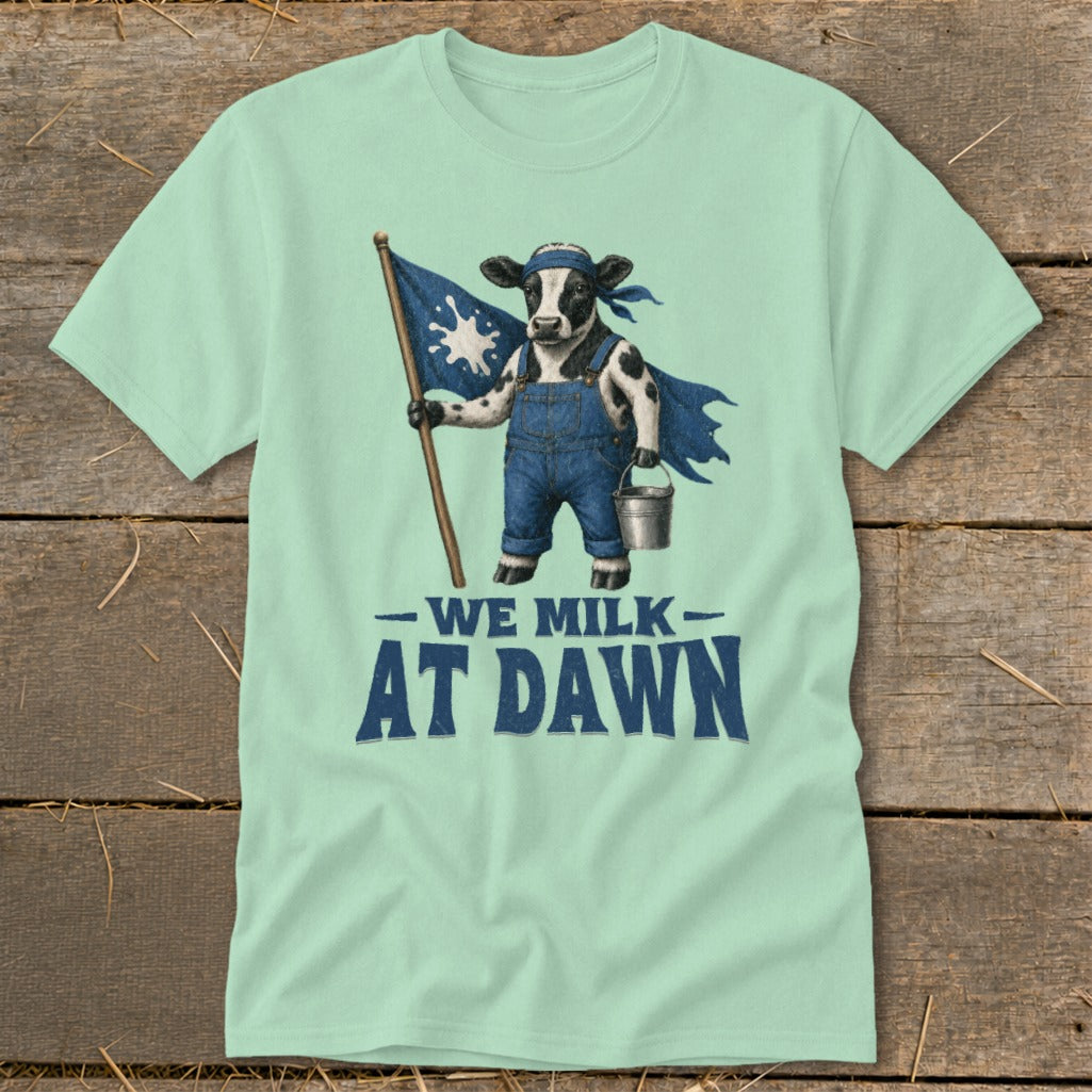 Cow wearing overalls and cape holding a flag and milk pail, text "We Milk At Dawn".