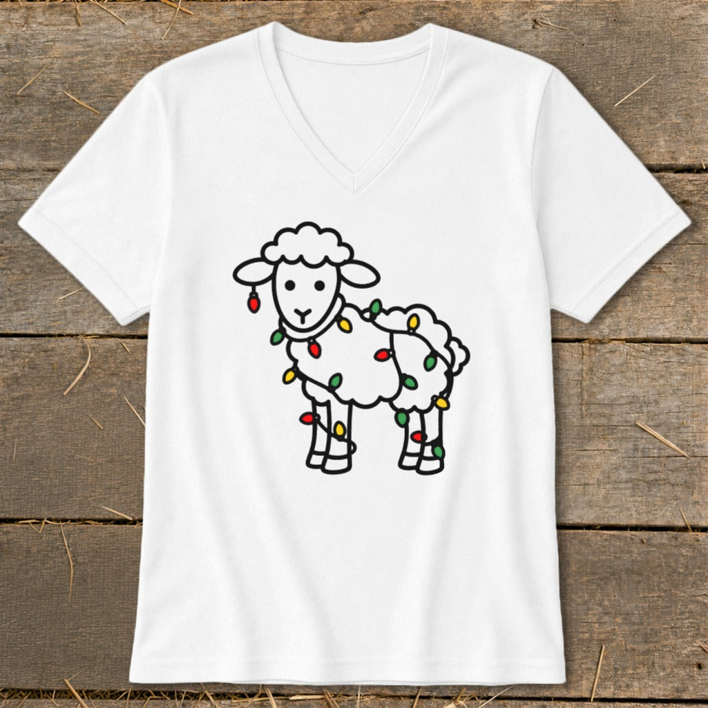 White v-neck t-shirt featuring a cartoon sheep wrapped in colorful Christmas lights, displayed on wooden planks.