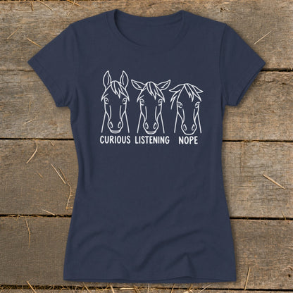 A dark blue women's t-shirt printed with three horse head outlines and the text "CURIOUS LISTENING NOPE" below them.