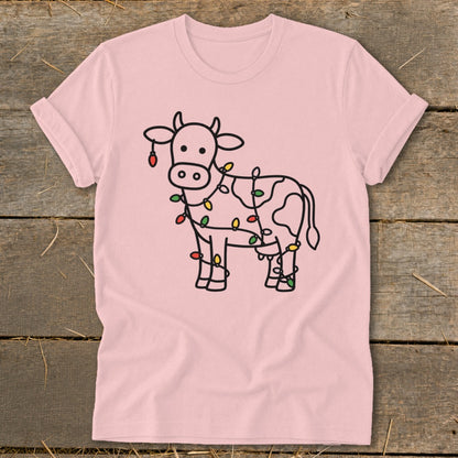 Pink t-shirt with a line drawing of a cow wrapped in colorful Christmas lights.