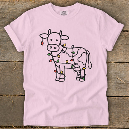 Pink t-shirt with a black outline drawing of a cow decorated with colorful Christmas lights.