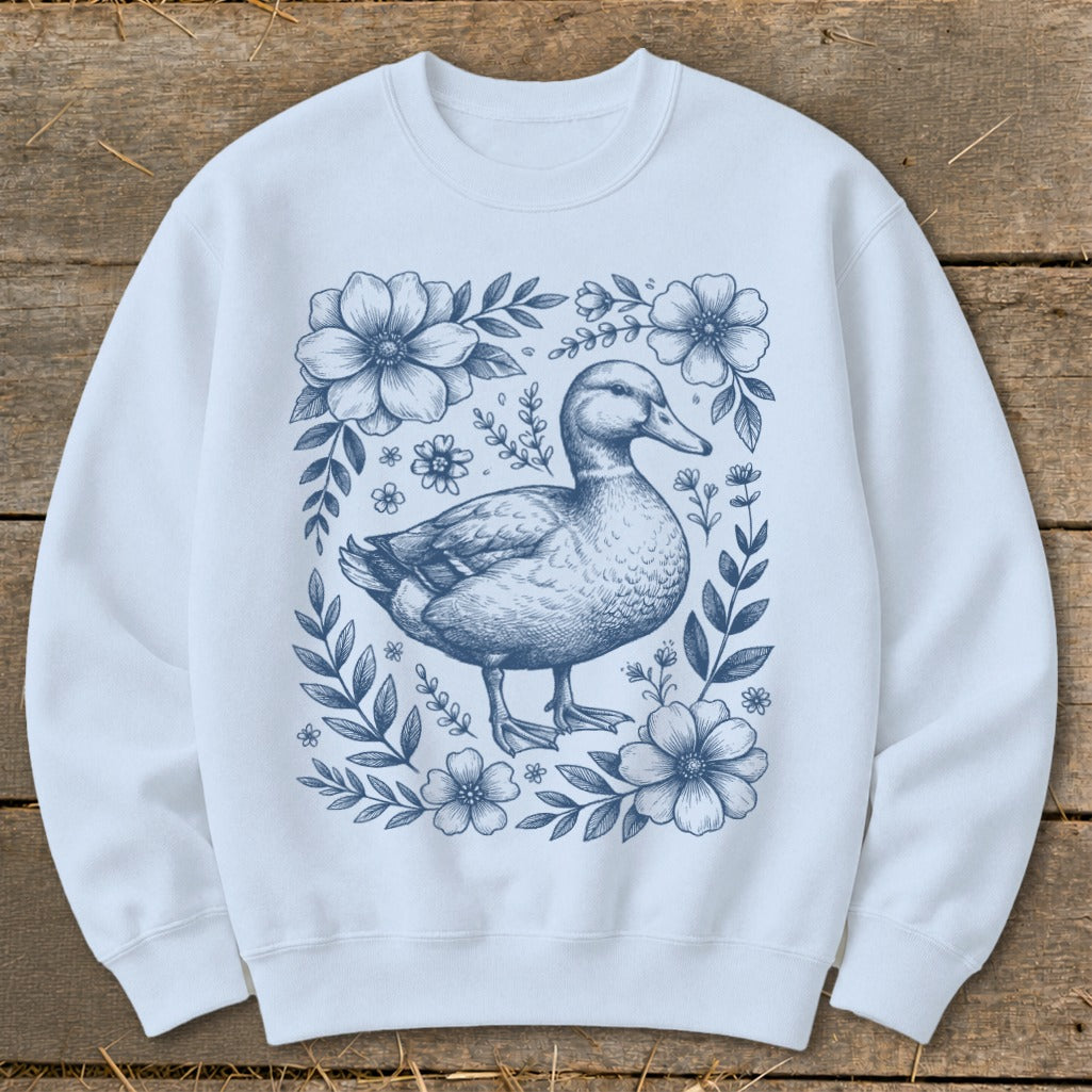 Light blue sweatshirt with a blue line drawing of a duck surrounded by floral elements.