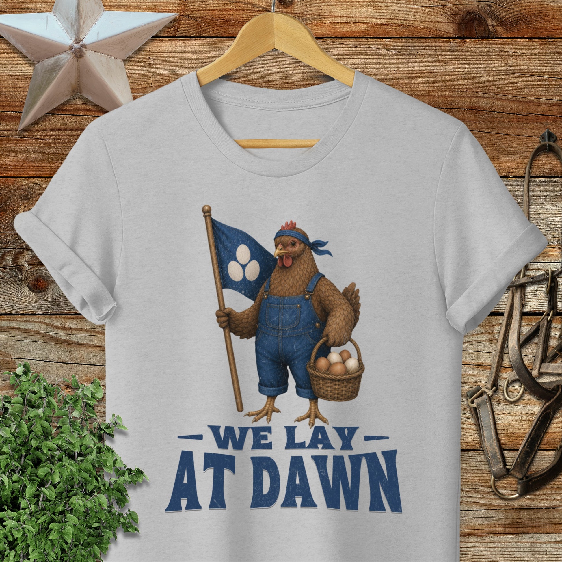 Chicken in overalls holding a flag and basket, text "WE LAY AT DAWN".