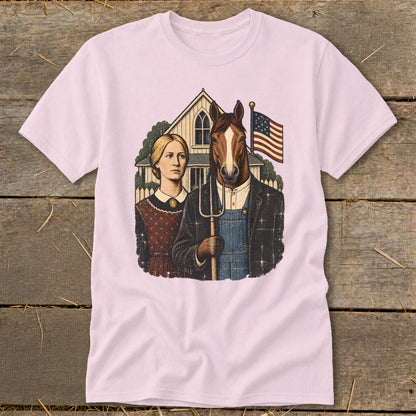 A light pink t-shirt featuring a humorous American Gothic parody graphic with a horse holding a pitchfork.
