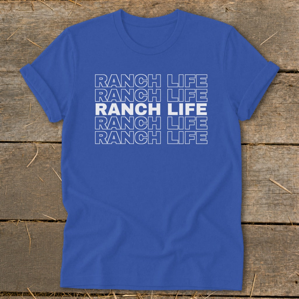 Royal blue short-sleeve t-shirt with stacked white RANCH LIFE text displayed centrally, laid flat on rustic wood.