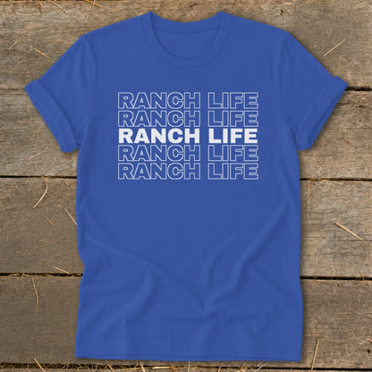 Royal blue short-sleeve t-shirt with stacked white RANCH LIFE text displayed centrally, laid flat on rustic wood.