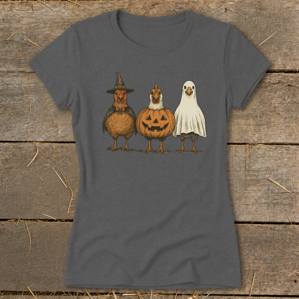 Three chickens dressed in Halloween costumes: witch, pumpkin, and ghost.