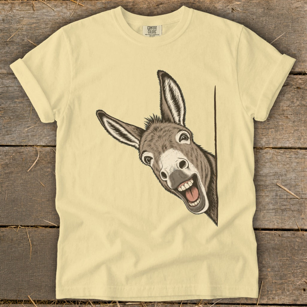 Donkey peeking from behind a corner with a wide grin on a pale yellow t-shirt.