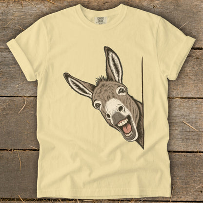 Donkey peeking from behind a corner with a wide grin on a pale yellow t-shirt.