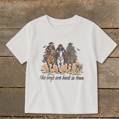 Three skeletal cowboys and a dog ride horses with text "The boys are back in town".