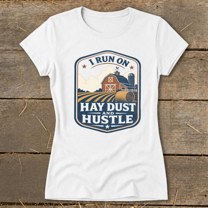 White t-shirt with "I Run On Hay Dust And Hustle" farm scene graphic.