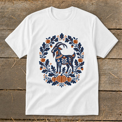 A white short-sleeved t-shirt features a folk-art graphic of a goat surrounded by an autumn wreath of leaves, pumpkins, and apples.