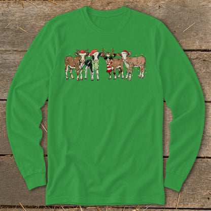 Five cartoon cows wearing Santa hats and Christmas lights on a green long-sleeved shirt.