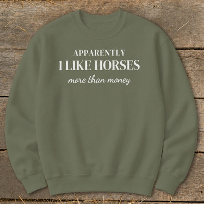 Olive green sweatshirt with white text: "APPARENTLY I LIKE HORSES more than money".