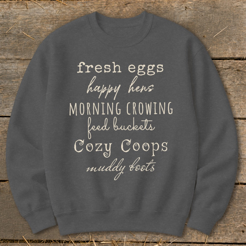 Dark grey sweatshirt with text: fresh eggs, happy hens, morning crowing, feed buckets, cozy coops, muddy boots.