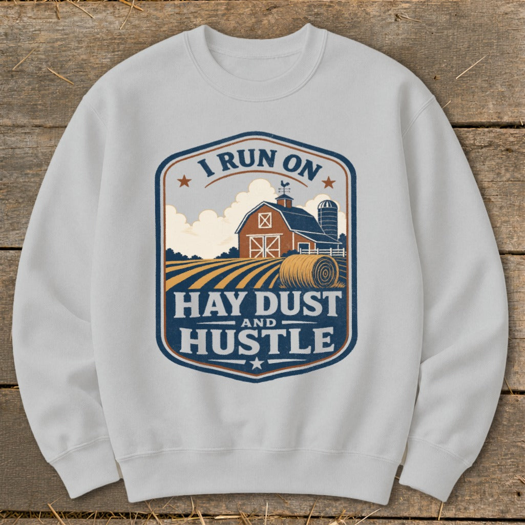 White sweatshirt with a rustic farm graphic and text "I RUN ON HAY DUST AND HUSTLE."