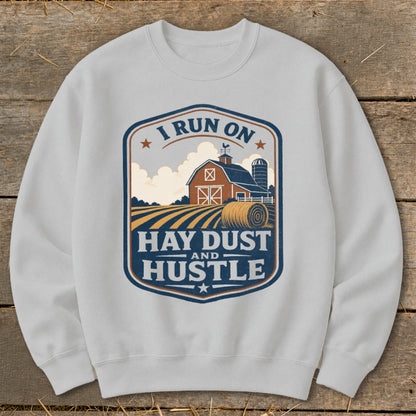 White sweatshirt with a rustic farm graphic and text "I RUN ON HAY DUST AND HUSTLE."
