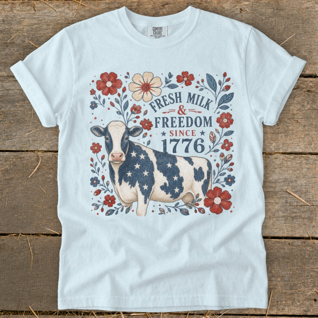 White t-shirt with patriotic cow and floral design, "Fresh Milk & Freedom Since 1776".