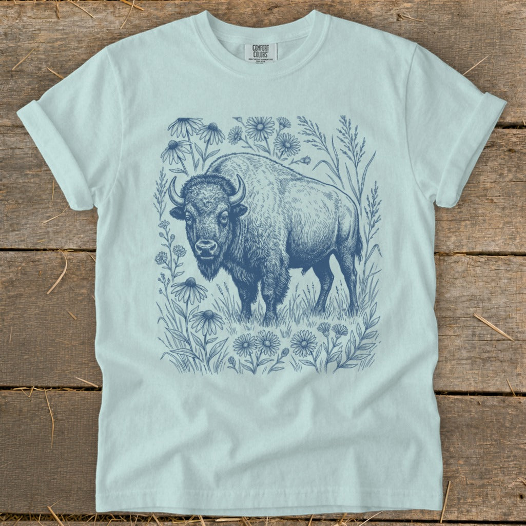 Blue line art bison standing in a field of wildflowers on a light blue t-shirt.
