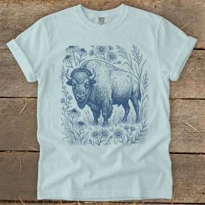 Blue line art bison standing in a field of wildflowers on a light blue t-shirt.