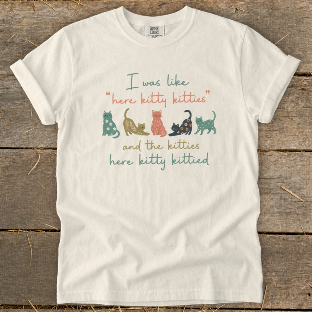 White t-shirt with "I was like 'here kitty kitties' and the kitties here kitty kittied" and cat illustrations.