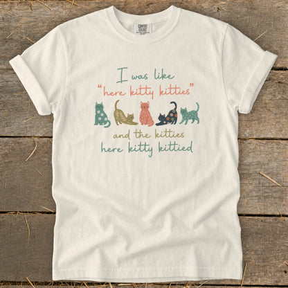 White t-shirt with "I was like 'here kitty kitties' and the kitties here kitty kittied" and cat illustrations.