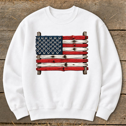 White crewneck sweatshirt featuring a graphic of an American flag made from painted wooden planks and horseshoes.