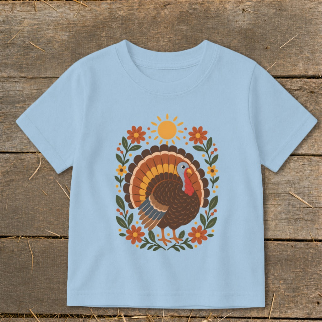 Light blue t-shirt with a cartoon turkey and floral design.
