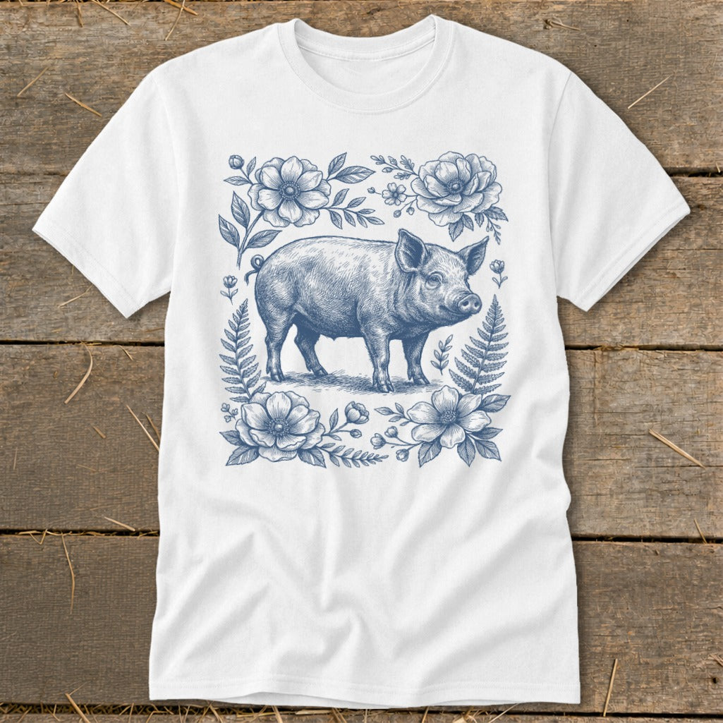 White t-shirt with a blue ink drawing of a pig surrounded by flowers and ferns.
