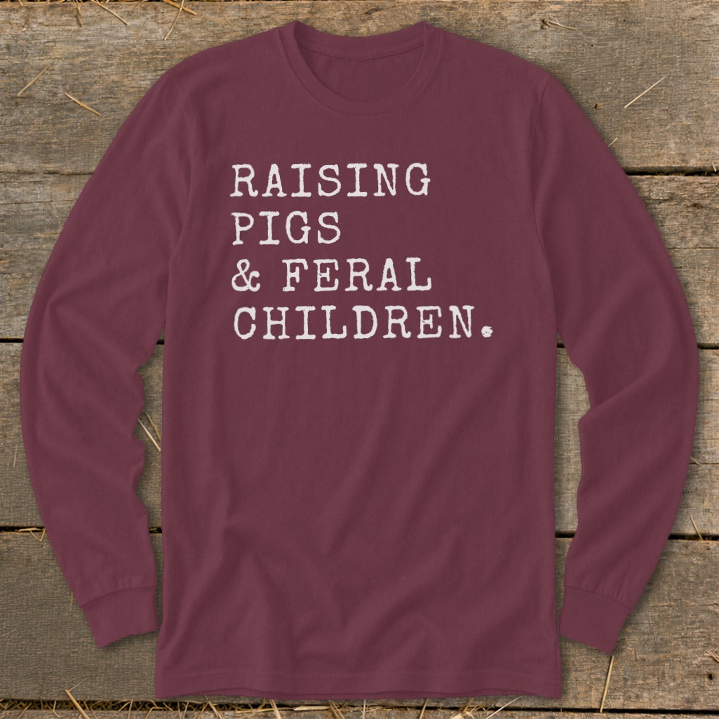 Maroon long-sleeve shirt with white text: Raising Pigs & Feral Children.