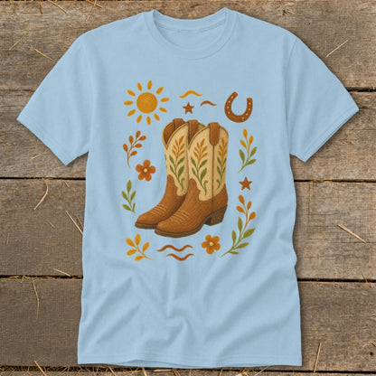 Light blue t-shirt with cowboy boots, sun, horseshoe, and floral design.