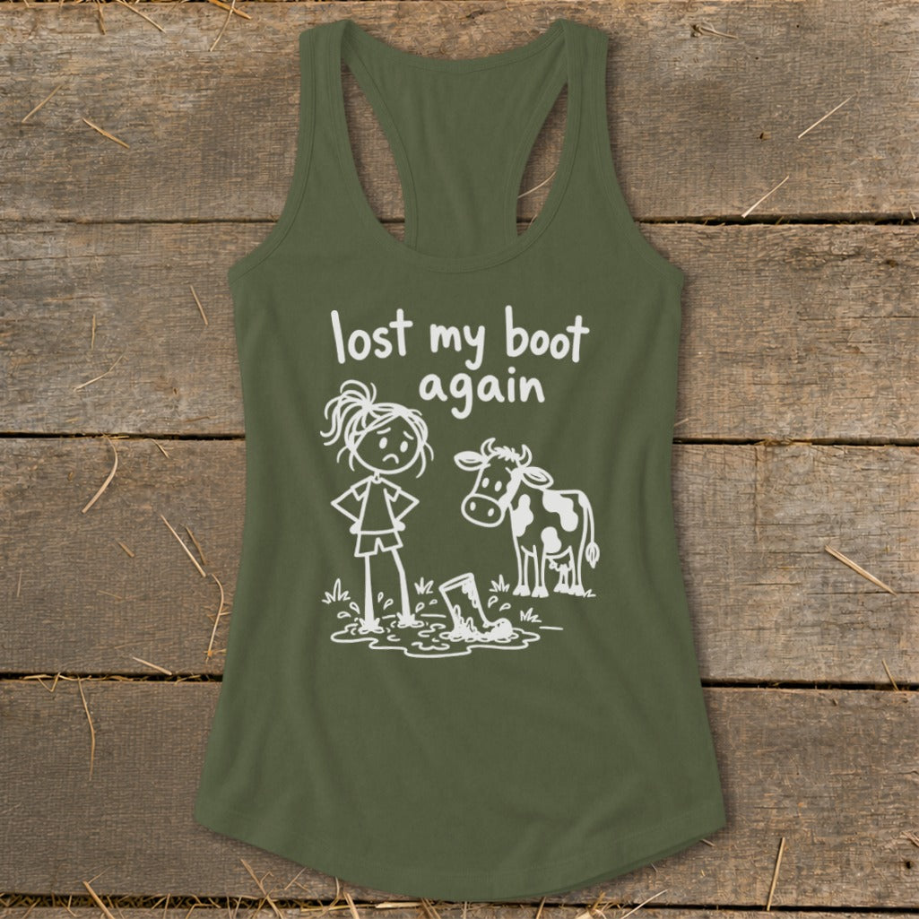 An olive green racerback tank top featuring a cartoon graphic of a sad girl and a cow beside a muddy boot, with text reading lost my boot again.
