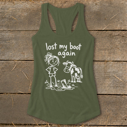 An olive green racerback tank top featuring a cartoon graphic of a sad girl and a cow beside a muddy boot, with text reading lost my boot again.