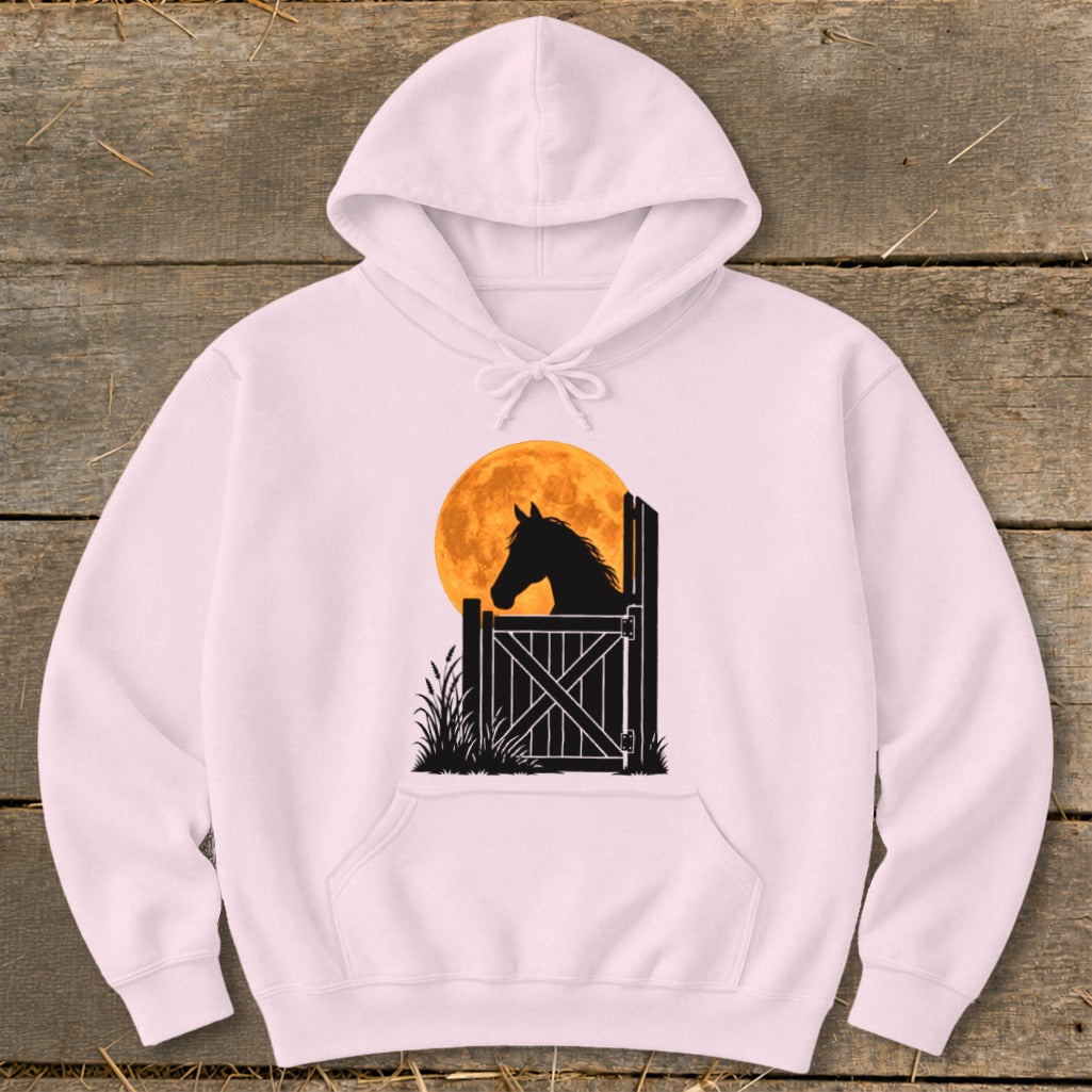 A light pink hooded sweatshirt featuring a graphic of a horse looking out a stable door against a large orange moon.