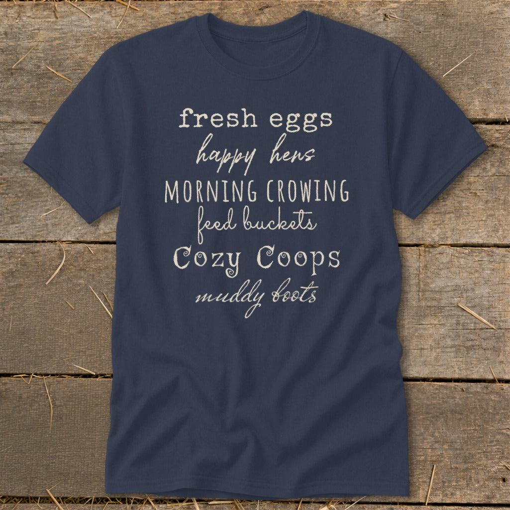 Navy t-shirt with "fresh eggs, happy hens, morning crowing, feed buckets, cozy coops, muddy boots" text.