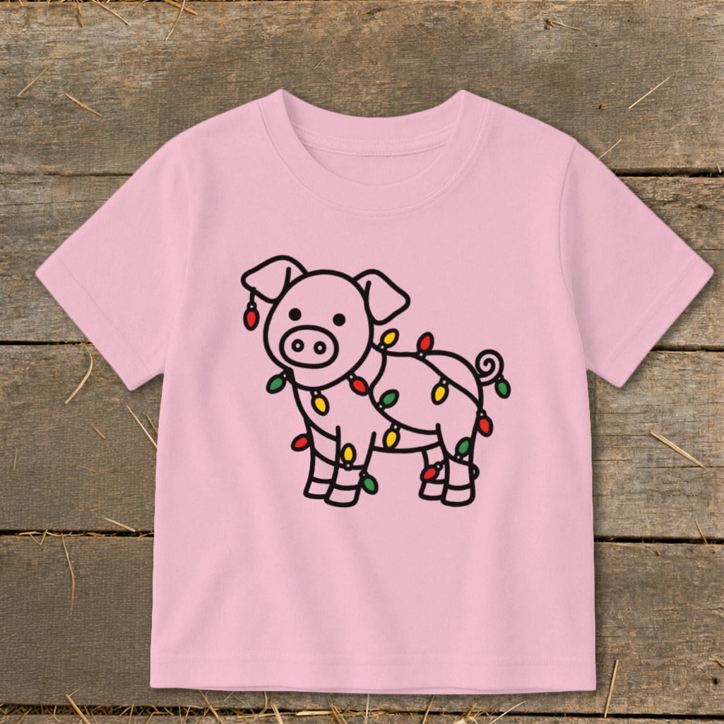 Light pink children's t-shirt featuring a line drawing of a pig tangled in Christmas lights.