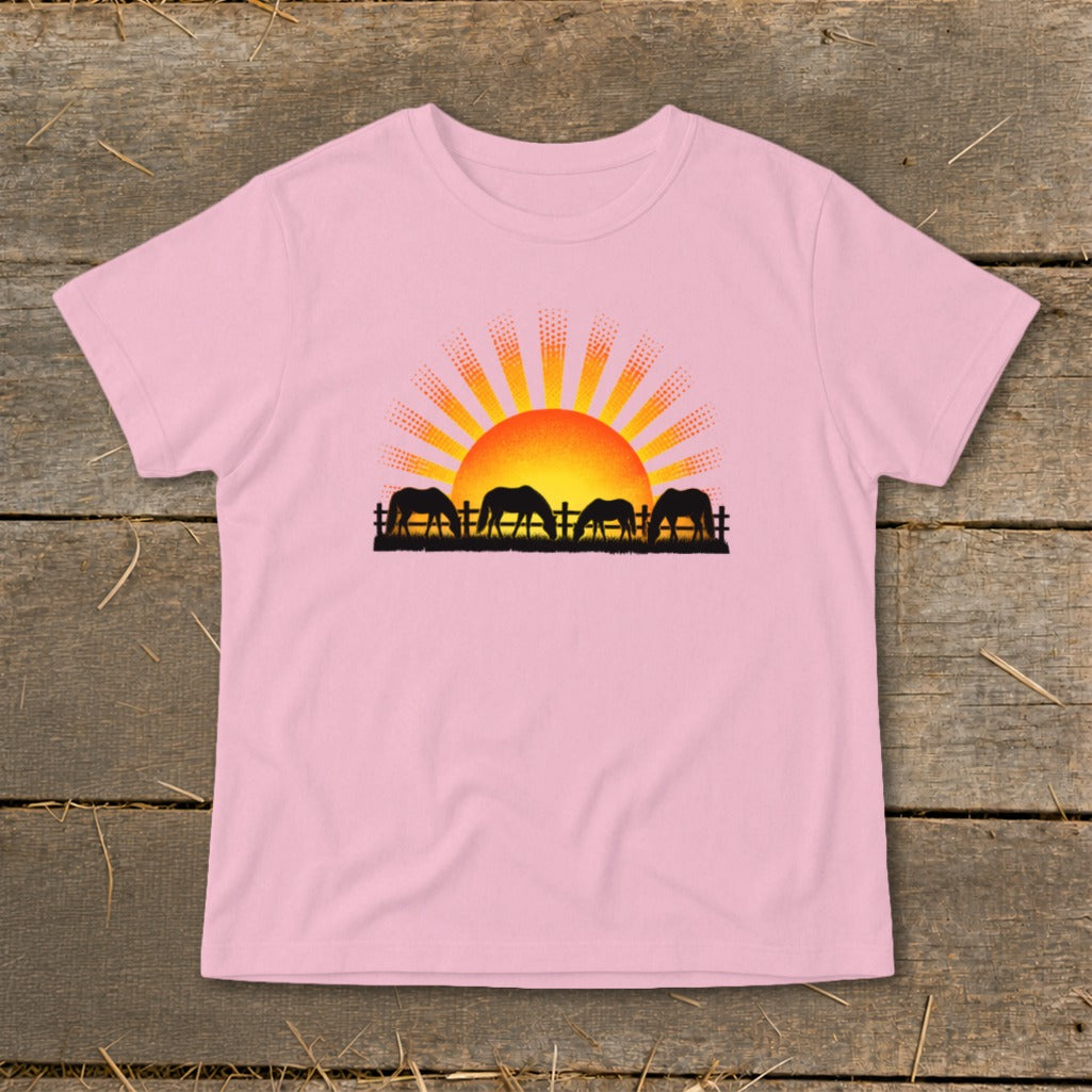 Pink t-shirt with silhouette of four horses grazing near a fence at sunset.