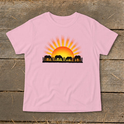 Pink t-shirt with silhouette of four horses grazing near a fence at sunset.