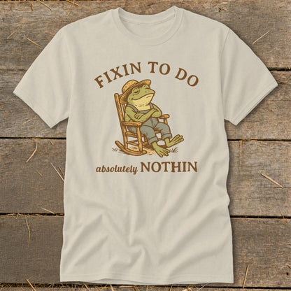 T-shirt with a frog in a rocking chair, text reads "Fixin to Do Absolutely Nothin".
