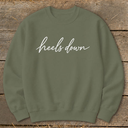 Olive green sweatshirt with white "heels down" text in cursive.