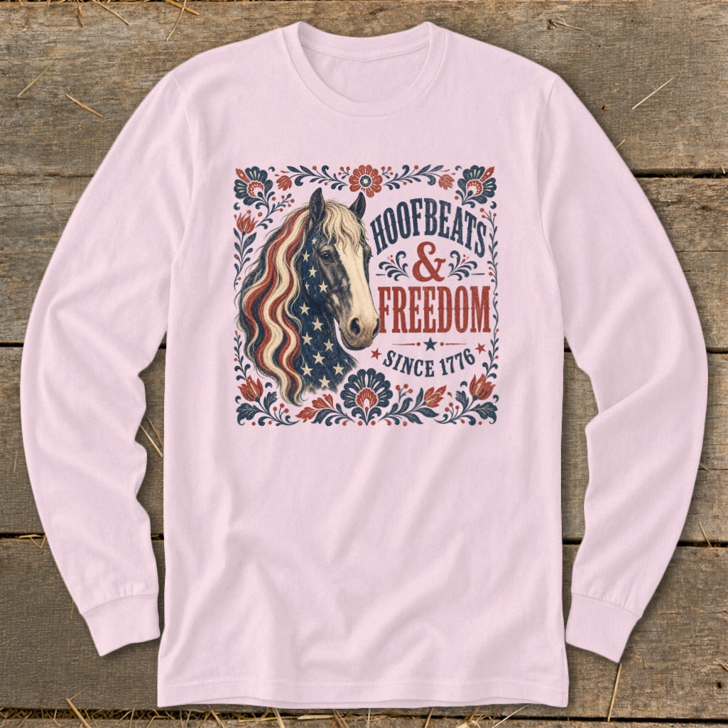 Horse graphic with US flag mane on pink long-sleeve shirt, reading "Hoofbeats & Freedom Since 1776".