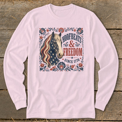 Horse graphic with US flag mane on pink long-sleeve shirt, reading "Hoofbeats & Freedom Since 1776".
